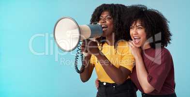 Dont keep calm, keep marching on. Studio shot of two young women using a megaphone against a blue background.