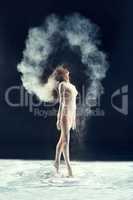 Studio muse. Studio shot of a young woman leaving a trail of powder in the air by whipping her hair.