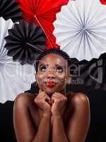 Her style is an ode to Japan. Studio shot of a beautiful young woman posing with a origami fans against a black background.