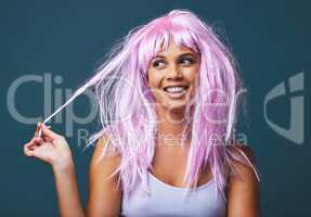 Wherever you go, take your own sunshine with you. Studio shot of a beautiful young woman posing with a playful pink wig against a blue background.