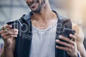 A gym membership is worth the investment for me. Closeup shot of a muscular young man using a cellphone and credit card in a gym.