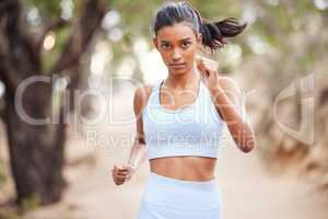 Ive never been fitter. Shot of a young woman jogging through a forest.