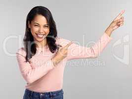 Take a look at this. Shot of a beautiful young woman pointing at copy space.