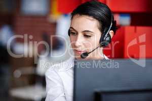 Assisting a client diligently. A pretty call center agent assisting a client diligently.
