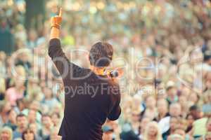 The crowd loves him. A singer performing in front of a massive crowd at a concert.