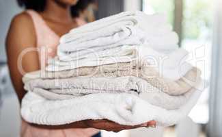 Theyre clean and ready to be used. Cropped shot of an unrecognizable woman carrying clean towels art home.