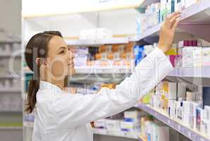 Finding exactly what a customer needs. Shot of an attractive young pharmacist checking stock in an aisle.