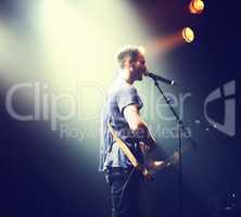 Music from the heart. Shot of a solitary musician playing guitar and singing into a mic.