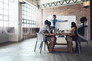 Directing his team through the plan. Shot of a mature businessman giving a presentation to his colleagues in an office.