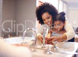 Lets get them good and clean. Cropped shot of a mother and daughter washing their hands at the bathroom sink.
