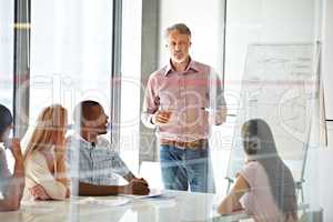 Sharing his experience and teaching them about business. Shot of a businessman presenting his ideas to his colleagues during a meeting.