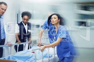 Rushing to the ER. Shot of a group of medical professionals rushing a patient on a gurney down a hospital corridor.