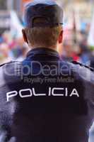 Hes got the situation under control. Rearview shot of a policeman wearing a uniform with the word, POLICIA on the back.