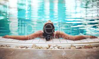 Sublime serenity. Shot of a young woman relaxing in the pool at a spa.
