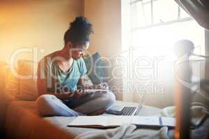 Immersed in her study material. Full length shot of a young female student studying at home.