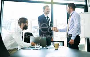 Getting the best of both business worlds with a merger. Shot of colleagues shaking hands during a formal meeting in an office.