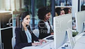 Were always busy solving problems. Cropped shot of a diverse group of businesswomen wearing headsets and using computers while sitting in the office together.