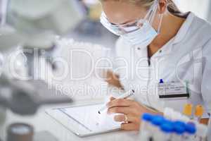 Making notes for her thesis. A young researcher recording her findings on a tablet in the lab.