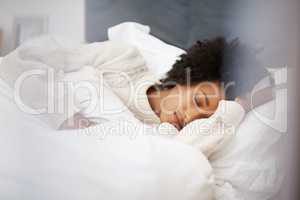 Deep in dreamland. Shot of a young woman sleeping in her bed at home.