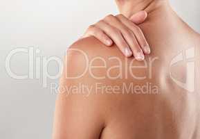 Whole body softness. Closeup studio shot of a woman touching her bare shoulder.