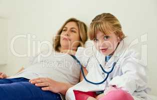 Mommys heart is so full of love its gonna explode. Portrait of an adorable little girl dressed up as a doctor and examining a woman with a stethoscope.