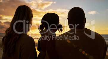 Silhouette closeup of happy family with one child on the beach looking at view at sunset. Two parents and daughter admiring golden sky and calm sea while enjoying their vacation and spending time