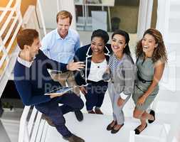 They share in their collective successes. Portrait of a group of coworkers having a meeting in a stairwell in a modern office.