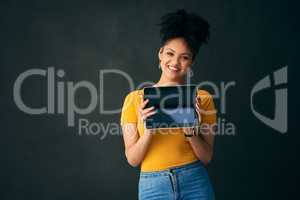 Like what you see. Shot of a young woman holding a digital tablet while posing against a grey background.