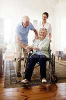 Surrounded by support. Shot of a smiling caregiver with a senior woman in a wheelchair and her husband at home.