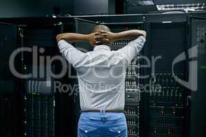 When the network is nuked. Rearview shot of an IT technician having difficulty repairing a computer in a data center.