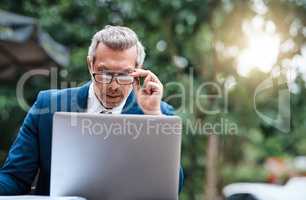 When working in a great place, great work can be produced. Shot of a handsome mature business in corporate attire using a laptop outside during the day.