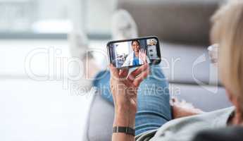 The most comfiest consultation ever. Shot of a senior woman using a smartphone to make a video call with her doctor on the sofa a home.