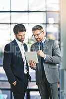 Finding ways to let their business prosper further. Cropped shot of two businessmen working together on a digital tablet in an office.