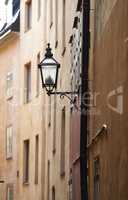 Cast iron street light in an alley way in a rural town in Europe. Empty street with glass lantern on tall buildings or houses. A hidden side street with traditional architecture and vintage lamp post