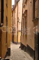 View of an empty, cobble street, alley between city buildings abroad in Stockholm, Gamla Stan. Narrow cobbled stone road in an old small overseas village. Exploring town, enjoying holiday and vacation