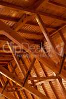 Beautiful sturdy wood architecture of interior roof or ceiling inside a house or building. Wooden beams and natural building material used for interior. Stained wood used for room ceiling feature