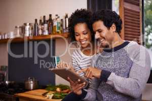 Lets download this recipe. Shot of a young couple using their tablet together while they get ready to prepare a meal.