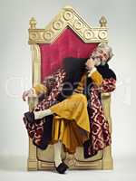 The thoughtful king. Studio shot of a richly garbed king sitting on a throne.