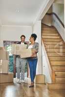 I can already imagine our little ones running around here. Full length shot of an affectionate young couple smiling while carrying boxes into their new home.