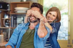 Think he knows its me. Portrait of a happy young woman playfully covering her husbands eyes.