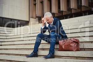 To be successful in business, you need to persevere. Shot of a dejected businessman sitting on the stairs outside his office with his head in his hands.