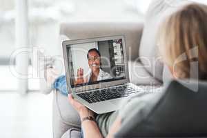 Curb the spread, have your checkup at home instead. Shot of a senior woman using a laptop to make a video call with her doctor on the sofa a home.