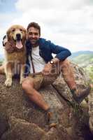 We made it to the top. Full length portrait of a handsome young man and his dog taking a break during a hike in the mountains.