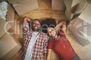 Glad to be sharing this milestone together. High angle shot of a young couple taking a break while moving into their new home.