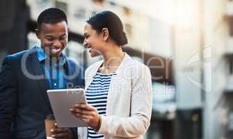 Sharing connections out in the open air. Shot of two businesspeople using a digital tablet in the city.