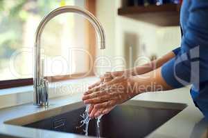 Washing up before dinner. Shot of an unrecognizable woman washing her hands in the kitchen sink.