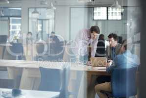 Hes got a lot of experience to offer the team. Shot of a group of colleagues talking together over a laptop in an office.