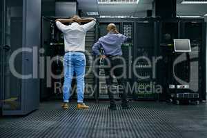 Meanwhile in the server room.... Rearview shot of two IT technicians having difficulty repairing a computer in a data center.