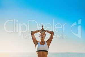 Chin up or the crown slips. Shot of an athletic young woman practicing yoga on the beach.