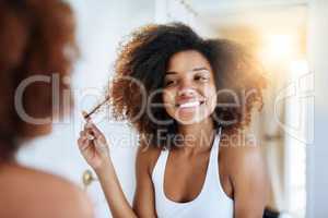 Keeping it real with her hair care routine. Shot of an attractive young woman going through her morning haircare routine.